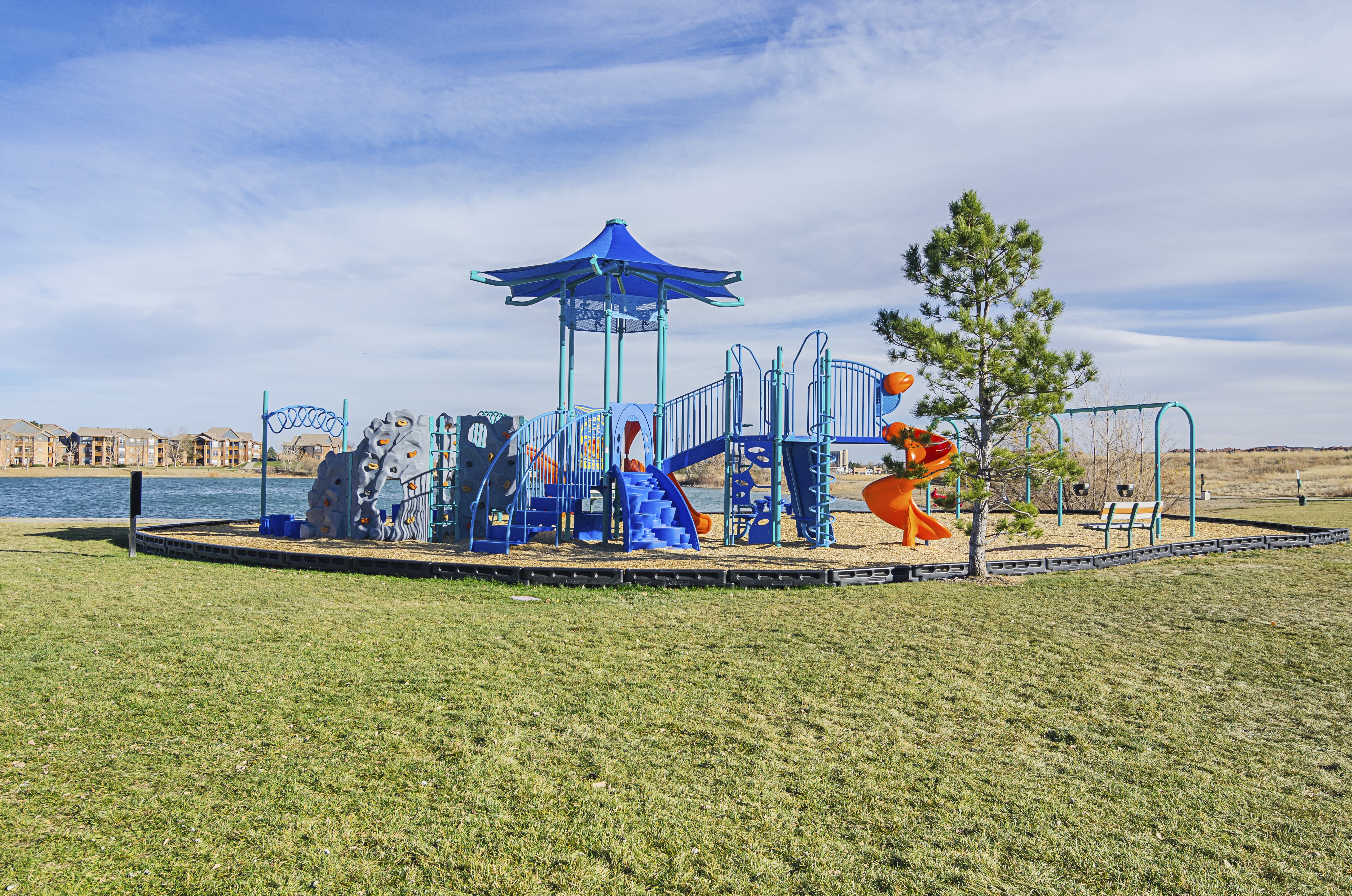 A playground with a blue canopy and a slide.